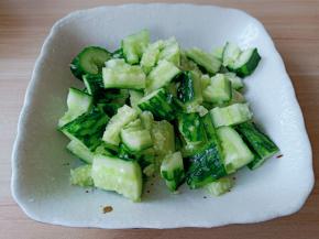 用刀背将黄瓜外面上的刺刮一下，清洗一下用刀背把黄瓜拍一下，再切成小段。