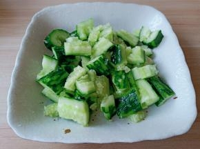 用刀背将黄瓜外面上的刺刮一下，清洗一下用刀背把黄瓜拍一下，再切成小段。