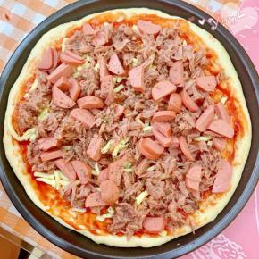 再把香肠和金枪鱼铺上，撒点披萨草。放入预热好的烤箱，上下火210度，中层，烤15分钟。取出撒上马苏里拉奶酪，210度再烤3分钟至奶酪融化即可。