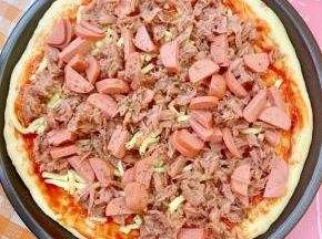 再把香肠和金枪鱼铺上，撒点披萨草。放入预热好的烤箱，上下火210度，中层，烤15分钟。取出撒上马苏里拉奶酪，210度再烤3分钟至奶酪融化即可。