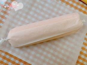 用擀面杖卷住油纸，顺势往上推，卷起来，两边跟拧糖一样拧起来。放入冰箱冷藏半小时后再切块食用。