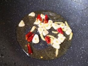 锅内重新倒入食用油烧热，下入蒜片姜丝和干红辣椒炒香。