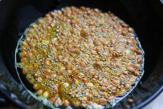 开小火慢慢炸，锅中开始冒泡后开始翻炒，炸至花生皮即将爆开就关火，