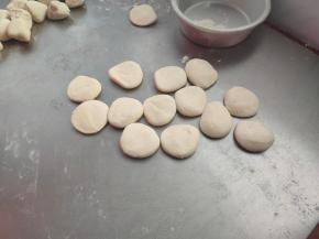 取出松弛好的面团，搓成长条，切成小剂子，压扁，擀成饺子皮。