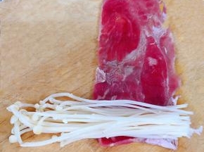 肥牛片展开取出适量金针菇放在肥牛的一侧