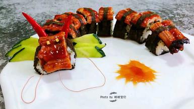 黄瓜摆在第一个寿司的后面上面插两个两个小红辣椒辣椒粒两个放在第一个鳗鱼片上做眼睛虾须子插在鳗鱼片下面就大功告成了