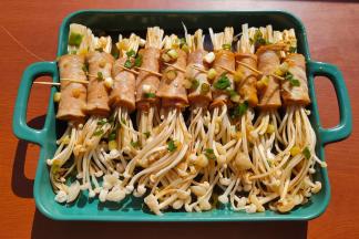 用小勺子把料汁一点点淋在培根金针卷上。