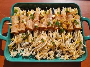 用小勺子把料汁一点点淋在培根金针卷上。