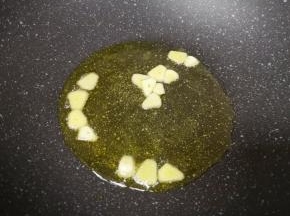 大蒜切成片，炒锅内倒适量的食用油烧热，下入蒜片炒香。