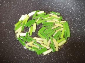 炒锅内倒适量的食用油烧热，下入葱段炒香。
