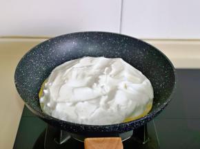 锅中放一张饼皮，把打发的蛋白均匀铺在上面，如图。