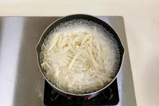 锅中倒入适量的清水煮开，金针菇去根放入锅中煮1分钟。