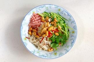 金针菇、胡萝卜、黄瓜、午餐肉丝、香菜、蒜蓉、小米辣、葱白和脆花生放入大碗中。
