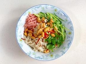 金针菇、胡萝卜、黄瓜、午餐肉丝、香菜、蒜蓉、小米辣、葱白和脆花生放入大碗中。