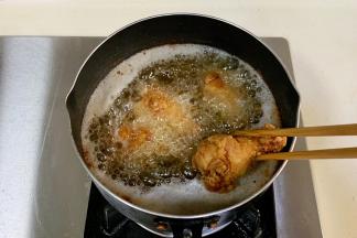 油温再次升高后，放鸡腿复炸1分钟捞出。