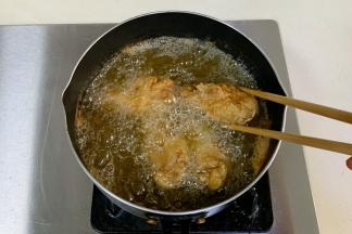 油六七成热时放鸡腿，小火慢炸约8分钟捞出。