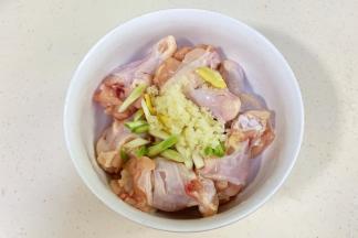 往鸡腿中加入小葱段、蒜蓉和姜片。