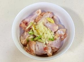 往鸡腿中加入小葱段、蒜蓉和姜片。