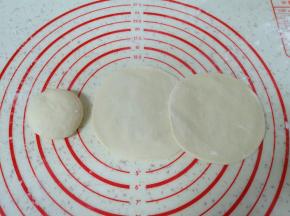 将分好的小剂子揉光滚圆压扁，擀成中间稍厚边缘薄的包子皮。