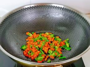 锅中留底油，加入胡萝卜丁青椒丁快速翻炒1分钟，盛出晾凉。