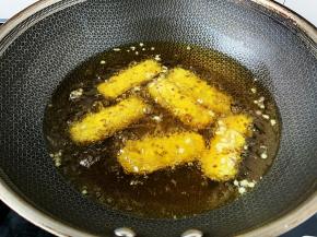 锅内放宽油，烧至五成热时下入牛肉棒小火炸制。