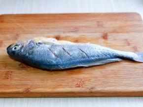 鱼放在砧板上，鱼身上用刀两面各划三刀，建议不要太深，避免影响颜值，哈～