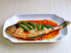 再把提前准备的葱姜摆放在鱼身上，包括鱼肚子里面也要塞一些。