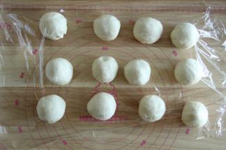 将面团分成12份。也是用折叠收圆的方法略微收圆，盖上保鲜膜松弛15分钟。