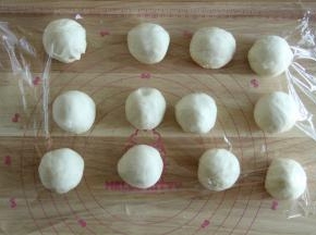将面团分成12份。也是用折叠收圆的方法略微收圆，盖上保鲜膜松弛15分钟。