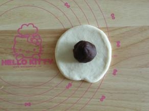 取一个松弛好的面团，擀开，翻面，放上一个馅料球。然后将面皮贴合在馅料球上，用右手虎口慢慢将面团收口，我习惯这样收口，比较均匀。收口一定要收紧，不然烤的时候容易漏馅料。