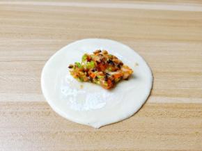 取一张饺子皮，在饺子皮的一圈都抹上水。