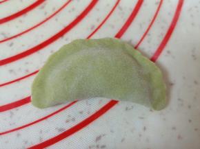 取一个蒸饺皮放上槐花馅，将边缘捏紧。