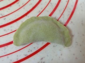 取一个蒸饺皮放上槐花馅，将边缘捏紧。