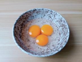 把三个鸡蛋嗑入碗里。