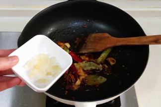 加入八角、桂皮、香叶、花椒、干辣椒和冰糖，炒至冰糖化开。