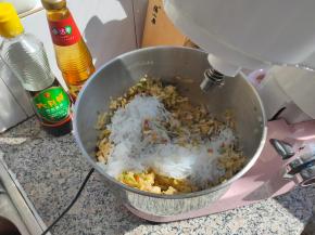 把泡软的粉条沥干水分，切碎后放入桶内，再加入亚麻籽油跟盐，再次拌匀。