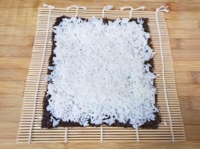 用勺子将米饭均匀的铺在紫菜上面压实。