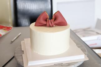 食用金粉用朗姆酒调成金色颜料，刷在蝴蝶结边缘，蛋糕上面的正中间放上一个公仔底托，将蝴蝶结放好。