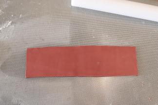 制作蝴蝶结：熟玉米淀粉和糖粉混合，撒少许在防粘垫上，深红色干佩斯擀成1-2毫米厚的薄片，切成长方形。