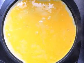 饼表面稍微定型后倒入鸡蛋液，抹平。喜欢葱花火腿丁的，可以在这一步撒在上面，或者直接拌在鸡蛋液里一起倒进饼上面