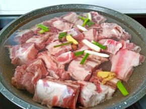 锅里放入牛排生姜葱段，料酒与适量的清水。