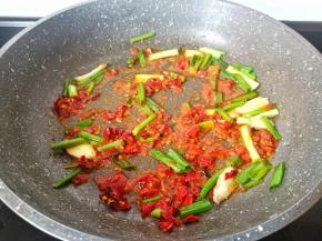 热锅凉油下郫县豆瓣酱、干辣椒段与葱段炒香。