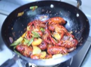 8，加入小龙虾炒，淋入少许的热水放蒸气上来入味到小龙虾中，继续炒一炒，最后加入蔬菜炒匀出锅。