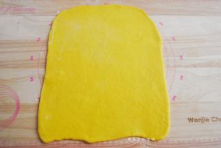 将黄色的面团擀成长约35cm，宽是24CM面片（宽度是土司盒的长度，普通的土司盒记得量一下）。
