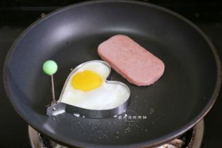 接着我们开始准备三明治的材料，因为面包是爱心形的，所以就煎一个爱心鸡蛋，再煎个培根肉，荤类的就准备好了。
