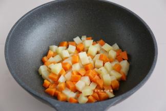 热锅，放入适量的油，爆香蒜末后倒入土豆和胡萝卜块，翻炒1分钟左右。