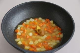 倒入2碗热水，大火煮沸，盖上锅盖焖2分钟，打开盖子试一下，土豆和胡萝卜够软后，把咖喱块放入锅里，用铲子轻轻搅拌，让咖喱块彻底融化。