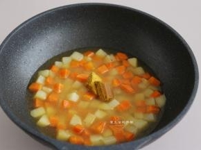 倒入2碗热水，大火煮沸，盖上锅盖焖2分钟，打开盖子试一下，土豆和胡萝卜够软后，把咖喱块放入锅里，用铲子轻轻搅拌，让咖喱块彻底融化。