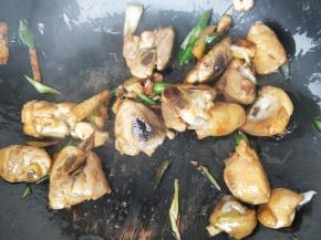 翻炒至鸡腿变色，加入大蒜苗段，加1勺生抽，继续翻炒