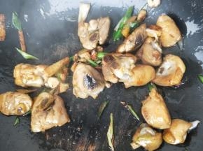 翻炒至鸡腿变色，加入大蒜苗段，加1勺生抽，继续翻炒